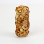 A Chinese carved russet jade amulet of a young dragon wrapped around a rock, L. 7.5cm.