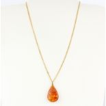 A large yellow metal mounted amber set pendant, L. 3.2cm, on an hallmarked 9ct yellow gold chain.