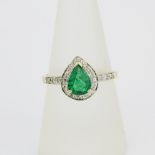 A hallmarked 9ct yellow gold ring set with a pear cut emerald surrounded by diamonds and diamond set