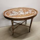 An oriental oval side table with extensive mother of pearl decoration to top, 64 x 49cm. Some mother