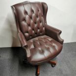 A revolving faux leather button backed office/ desk chair on castors, H. 104cm.