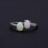 A 10ct yellow gold (marked 10K) ring set with oval cabochon opals and diamond set shoulders, (U.5).