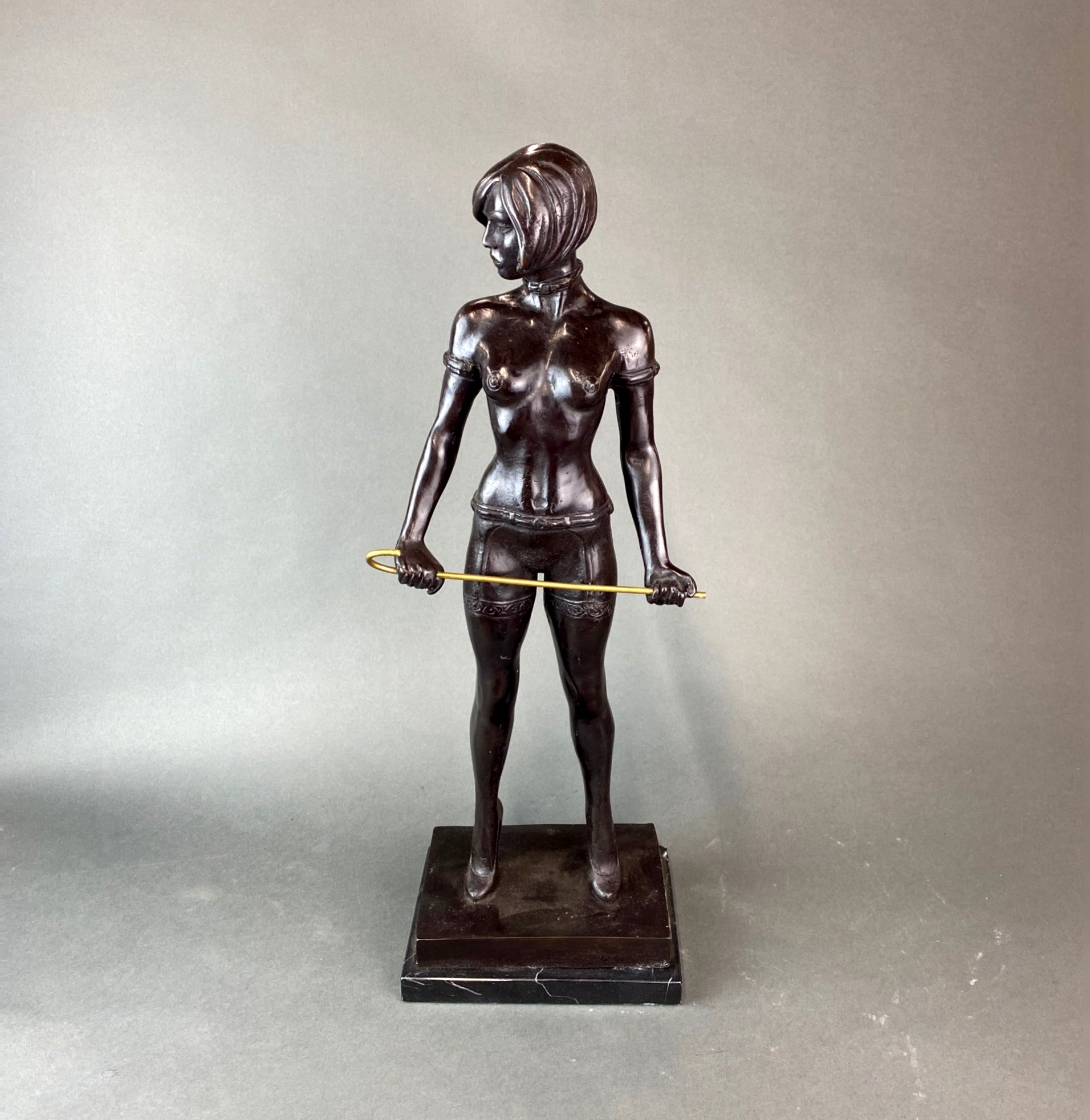 A large bronze figure of Miss Whiplash with a black marble base, H. 56cm.