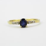 A 9ct yellow gold ring set with an oval cut sapphire and diamonds, (O).