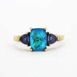 A hallmarked 9ct yellow gold ring set with a faceted cut blue mystic topaz and trillion cut