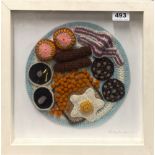 A framed crocheted woollen 'picture' of a full English breakfast, pencil signed Kate Jenkins, 34 x