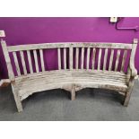 A large curved garden bench with an inscribed message, two back panels missing, L. 237cm H. 90cm.