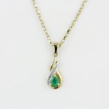 A yellow metal emerald and diamond set pendant on a hallmarked 9ct yellow gold chain, L. 44cm.