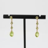 A pair of 9ct yellow gold drop earrings set with round and oval cut peridot, L. 2.5cm.