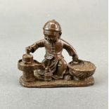 A Chinese bronze figure of a young boy, possibly preparing rice flour. L. 7.5cm. H. 5.5cm.
