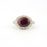 A hallmarked 9ct yellow gold ring set with a large oval cut ruby and diamonds, ruby L. 1.2cm, (O).