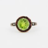 An antique rose metal (tests 9ct gold) ring set with a large round peridot surrounded by rubies (
