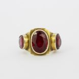 A heavy 14ct yellow gold (tested) ring set with three large oval and round cut rubies, largest