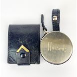 A cased Harrods pocket clock, Dia. 5cm. together with a fifty year calender and a further Leonard