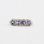 A hallmarked 9ct white gold ring set with round cut tanzanites and diamonds, (L.5).
