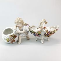 A 19th century German porcelain figure of a cherub with a basket, H. 21cm. together with a further