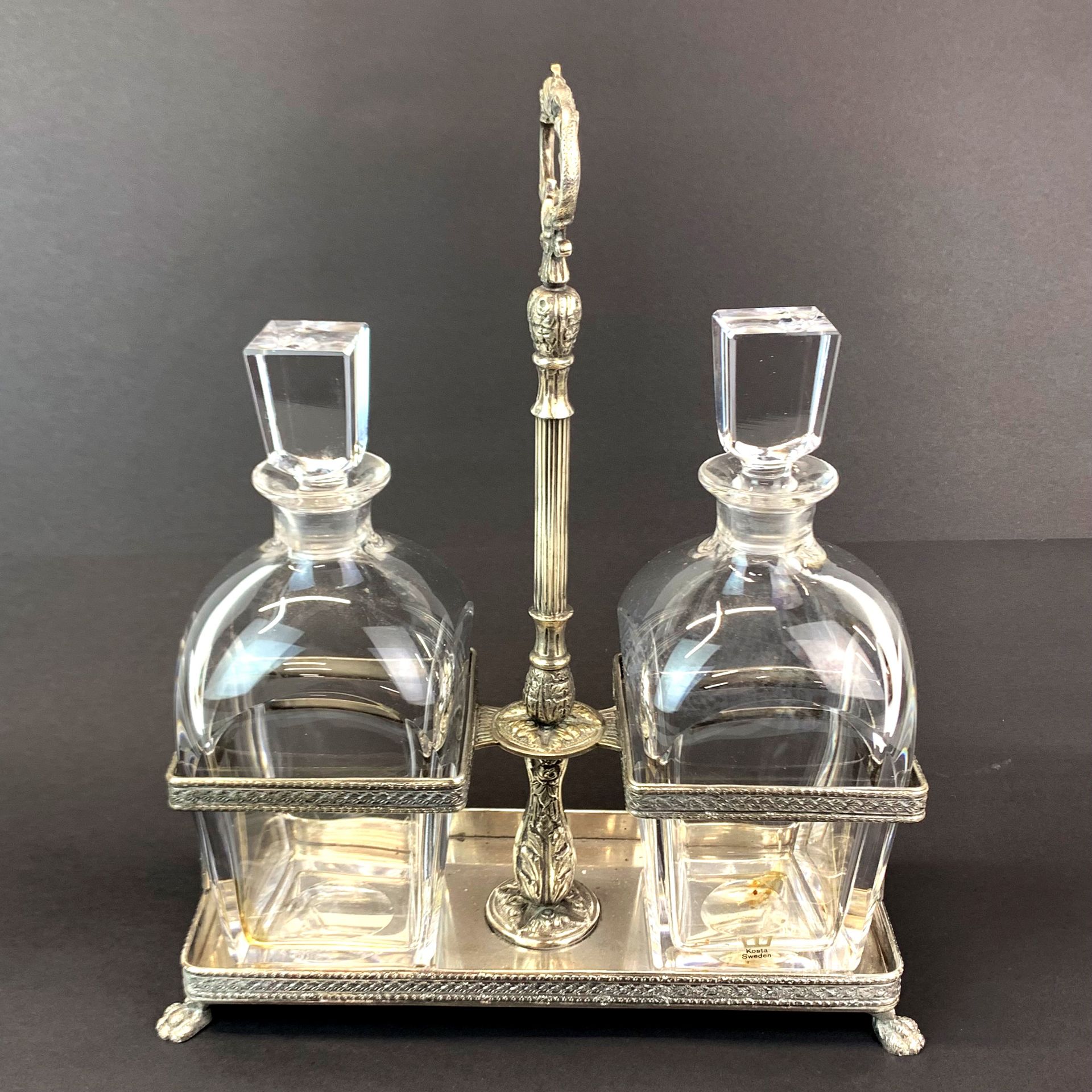 A silver plated decanter stand with two Kosta Sweden decanters, W. 25cm. H. 30cm.