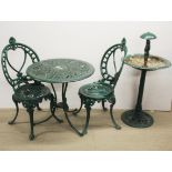 A cast metal garden table and two chairs together with a cast metal bird bath, table Dia. 67cm.