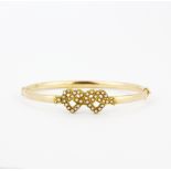 A 15ct rose and yellow gold bangle set with seed pearls, inner W. 6cm.
