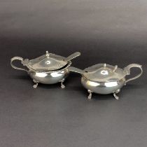 A pair of hallmarked silver mustard pots with blue glass liners, one liner repaired. with hallmarked