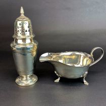 A hallmarked silver sugar shaker with a hallmarked silver sauce boat.