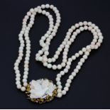 A stunning double strand white coral bead necklace with a 14ct yellow gold and carved coral clasp