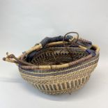 A wood and leather bull whip with a hand woven basket.