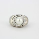 A heavy 18ct white gold 'De Beers' ring set with a cultured pearl surrounded by diamonds, (N).