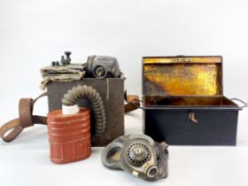 A wartime morse signalling lamp with a gas mask and a deed box.