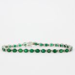 An 18ct white gold (stamped 750) tennis bracelet set with oval cut emeralds and brilliant cut