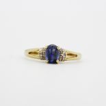 A 9ct yellow gold ring set with a cabochon cut sapphire and diamond set shoulders, (N.5).