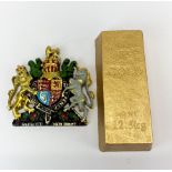 A gilt cast iron block resembling a gold bar, 9 x 21cm. together with a painted resin royal coat