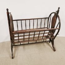A child's rocking crib with turned wooden supports, L. 105cm H. 100cm.