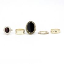 A group of five silver rings, including wedding bands and a full eternity ring.