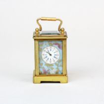 A miniature brass carriage clock with porcelain panels, H. 7cm.