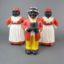 Three painted cast iron money box doorstops. H. 28cm.