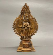 A gilt bronze figure of a standing multi head and multi arm deity with shrine, H. 41cm.