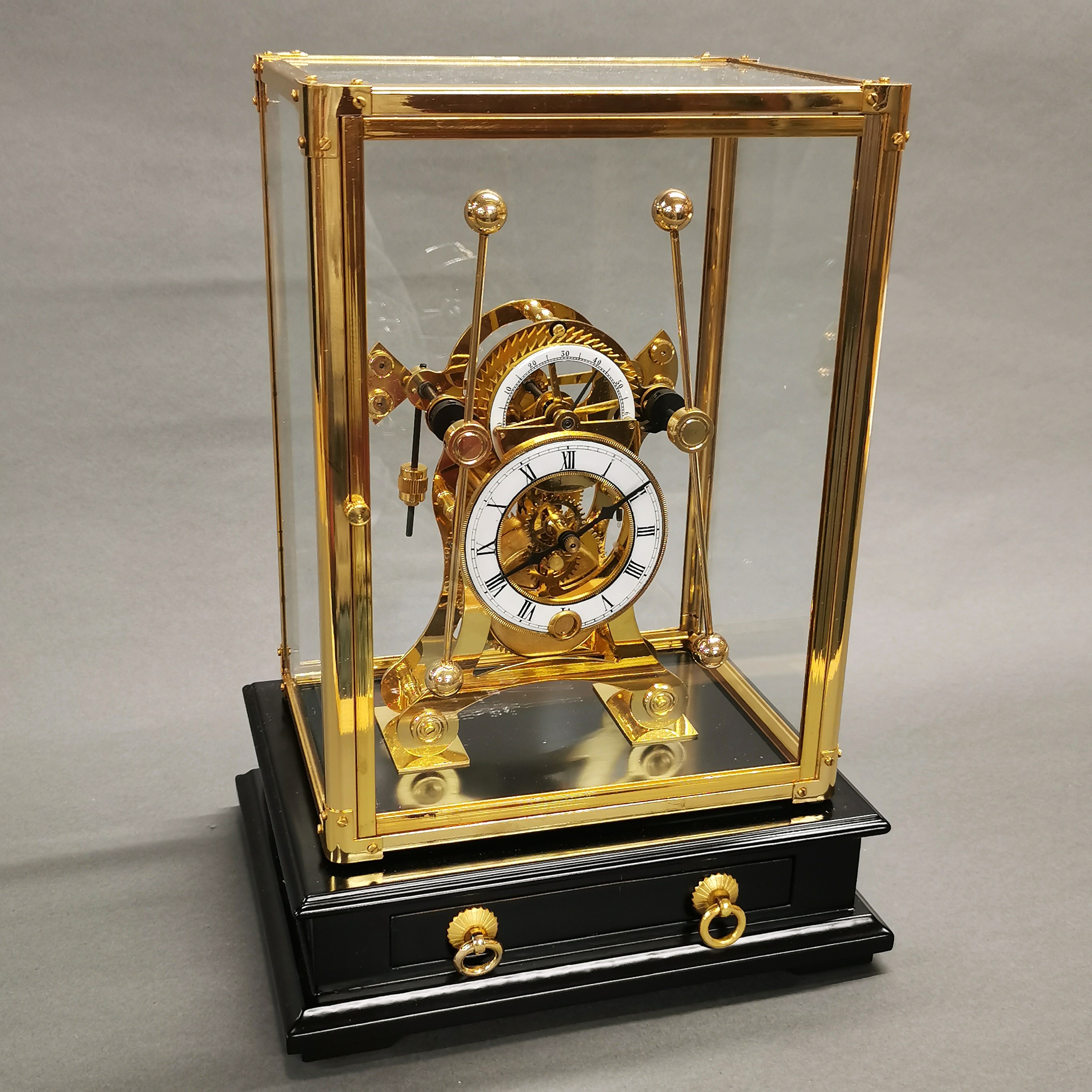 A brass and glass cased grasshopper clock. Case size 24 x 20 x 14cm.