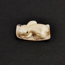A carved fossilised mammoth tusk signed Netsuke of a rabbit.