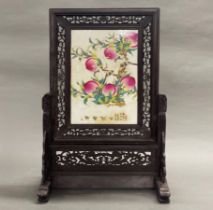 A Chinese porcelain and hardwood table screen, decorated with peaches, H. 68cm.