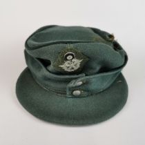 A World War Two German cloth cap with military police badge.