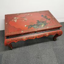 A Chinese red lacquer carved low table with chinoiserie decoration, 110 x 70 x 45cm.