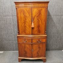 A mahogany veneered cabinet with pull out writing shelf, two drawers and flame mahogany decoration