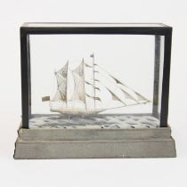 A glass cased white metal filigree model of an Eastern sailing ship, 23 x 18 x 9cm.