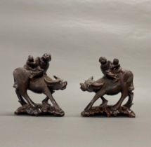 A pair of Chinese carved hardwood figures of buffaloes with children and glass eyes, L. 19cm.