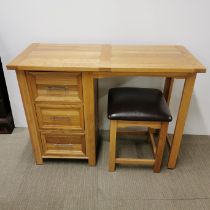An oak three drawer desk with an oak and faux leather stool, 105 x 77 x 44cm.