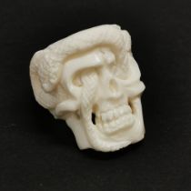 A hand carved buffalo bone ring of a snake entwined through eye sockets.