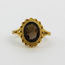 A hallmarked 9ct yellow gold ring set with an oval cut brown tourmaline, (K).