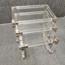 A nest of three Charles Hollis Jones style lucite and glass topped tables with gilt metal edges,