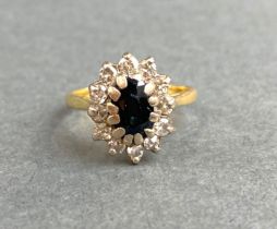 An 18ct yellow gold cluster ring set with an oval cut sapphire surrounded by diamonds, (O).